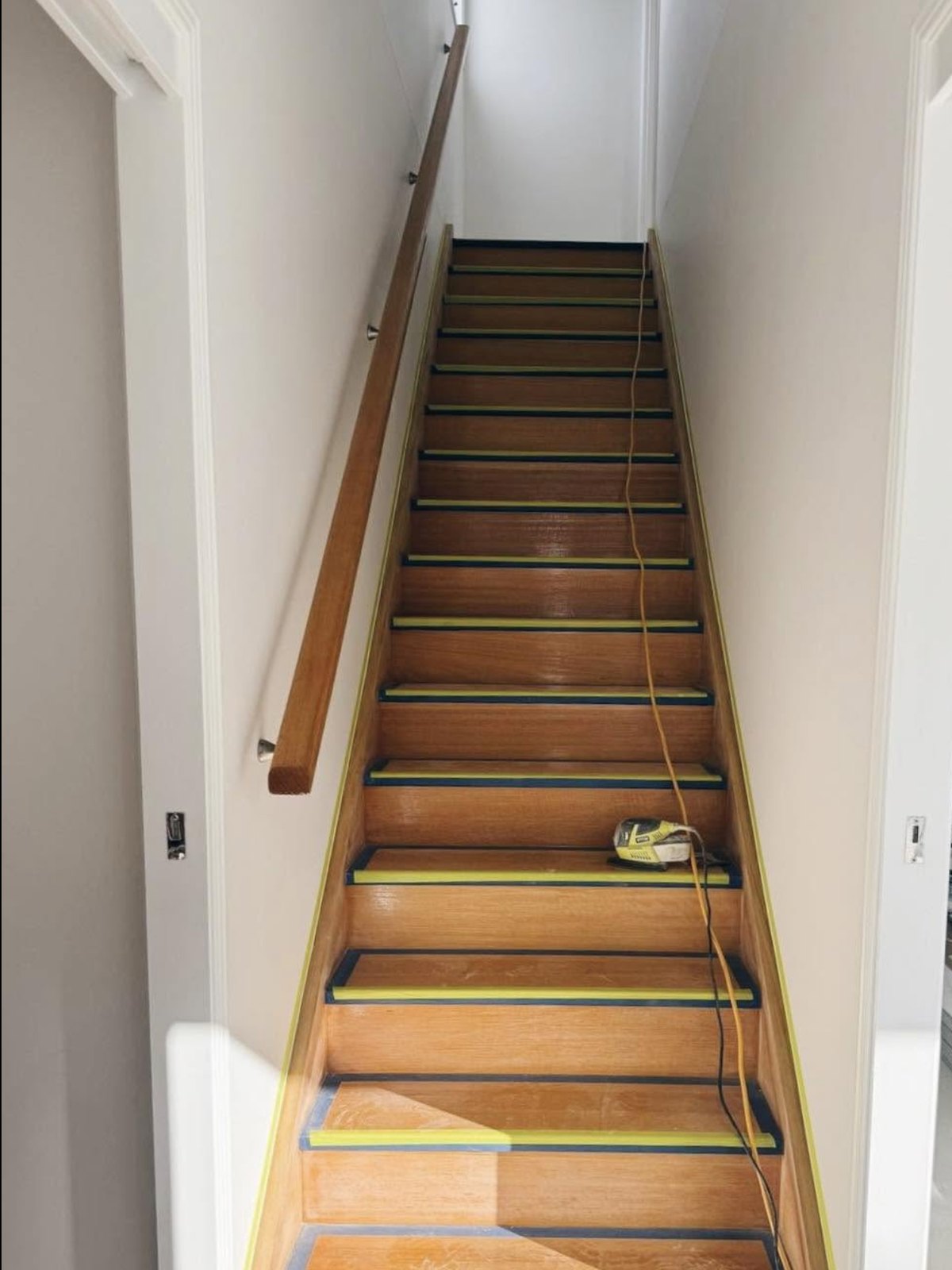 Staircase masked with tape and sanding tools in place before painting